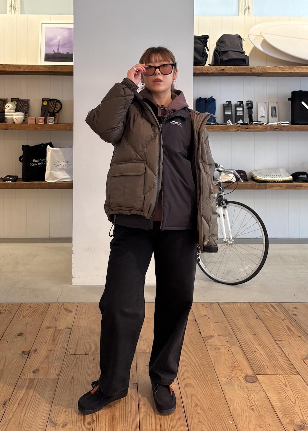 ブラック系のデニムパンツ、グリーン系のダウンジャケット/コート、ブラウン系のパーカーを着用したレディースの冬コーディネートの4枚目の写真