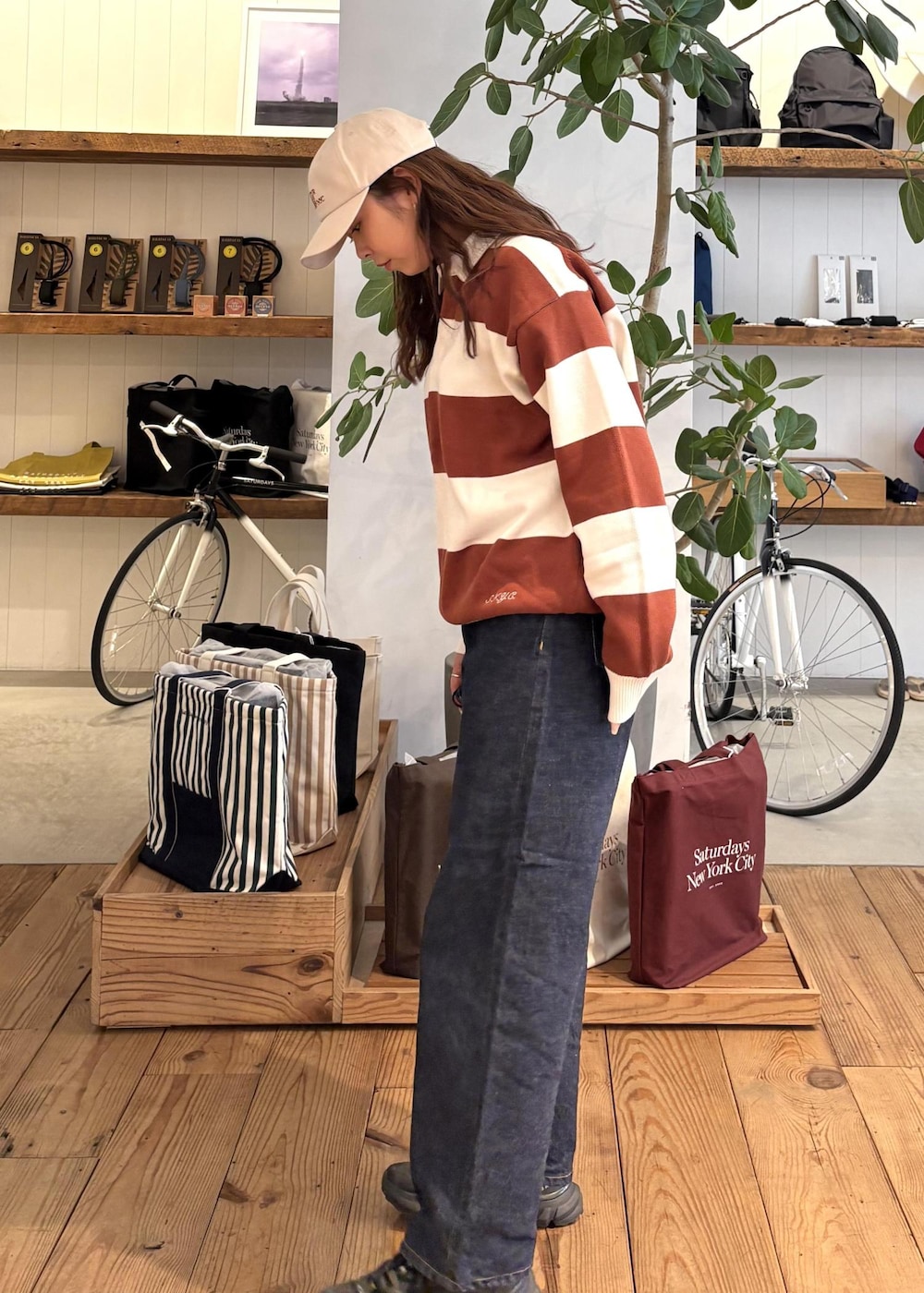 ブルー系のデニムパンツ、オレンジ系のスウェット、ホワイト系のキャップを着用したレディースの冬コーディネートの3枚目の写真