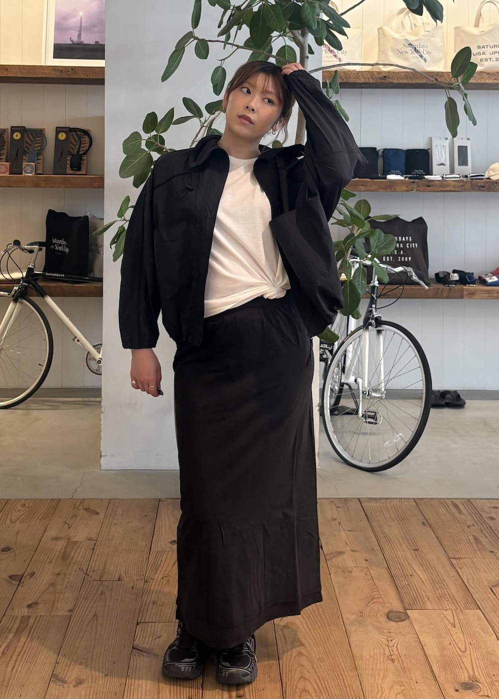 ブラック系のスカート、ブラック系のブルゾン、ホワイト系のTシャツ/カットソーを着用したレディースの春コーディネートの2枚目の写真