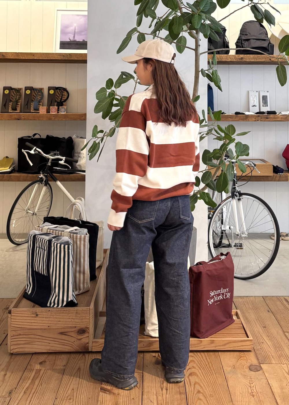 ブルー系のデニムパンツ、オレンジ系のスウェット、ホワイト系のキャップを着用したレディースの冬コーディネートの4枚目の写真