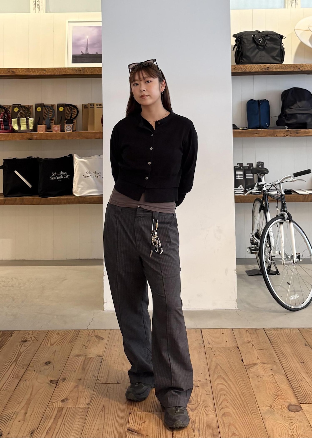 グレー系のスラックス、ブラック系のカーディガン/ボレロ、ブラウン系のサングラスを着用したレディースの秋コーディネートの2枚目の写真