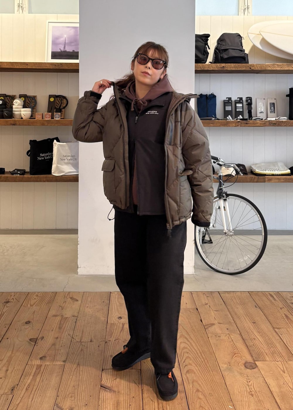 ブラック系のデニムパンツ、グリーン系のダウンジャケット/コート、ブラウン系のパーカーを着用したレディースの冬コーディネートの5枚目の写真