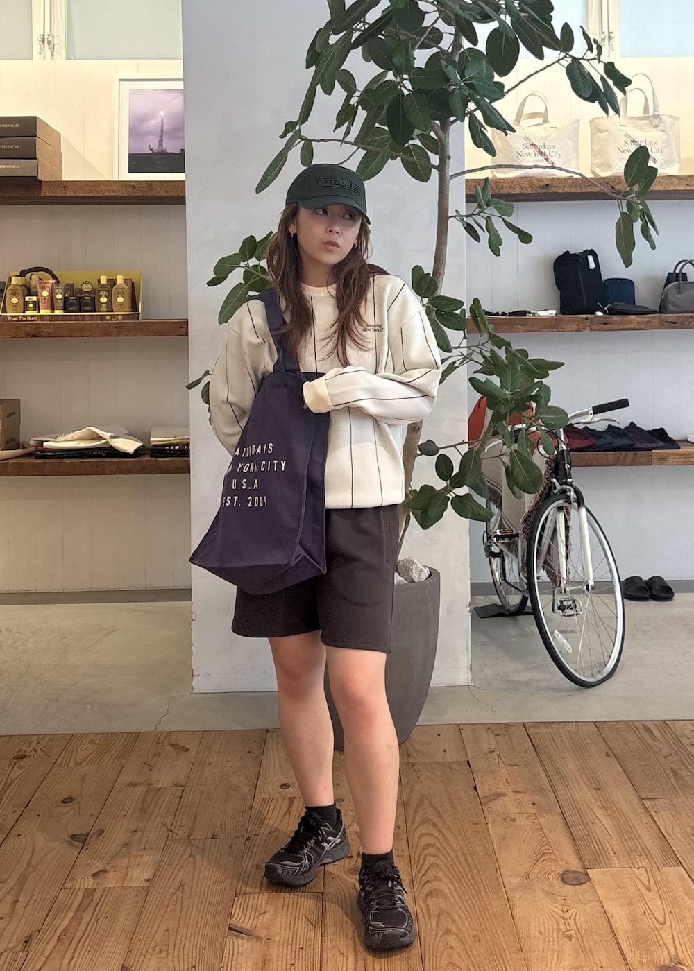 ブラック系のその他パンツ、パープル系のトートバッグ、グリーン系のキャップを着用したレディースの秋コーディネートの2枚目の写真