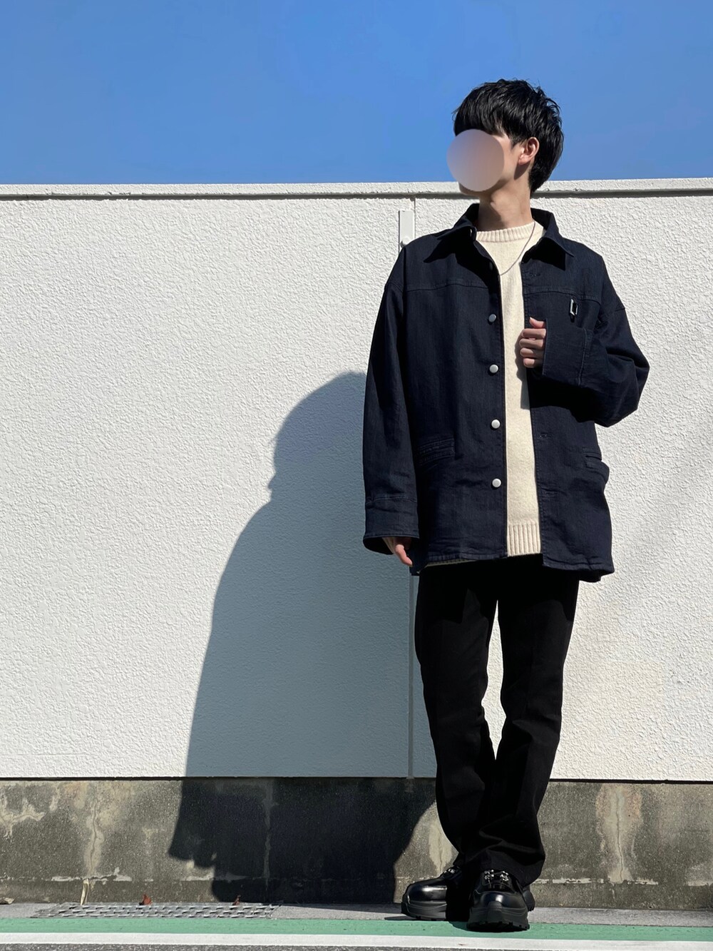 ブルー系のブルゾン、ホワイト系のニット/セーター、ブラック系のデニムパンツを着用したメンズの秋コーディネートの2枚目の写真