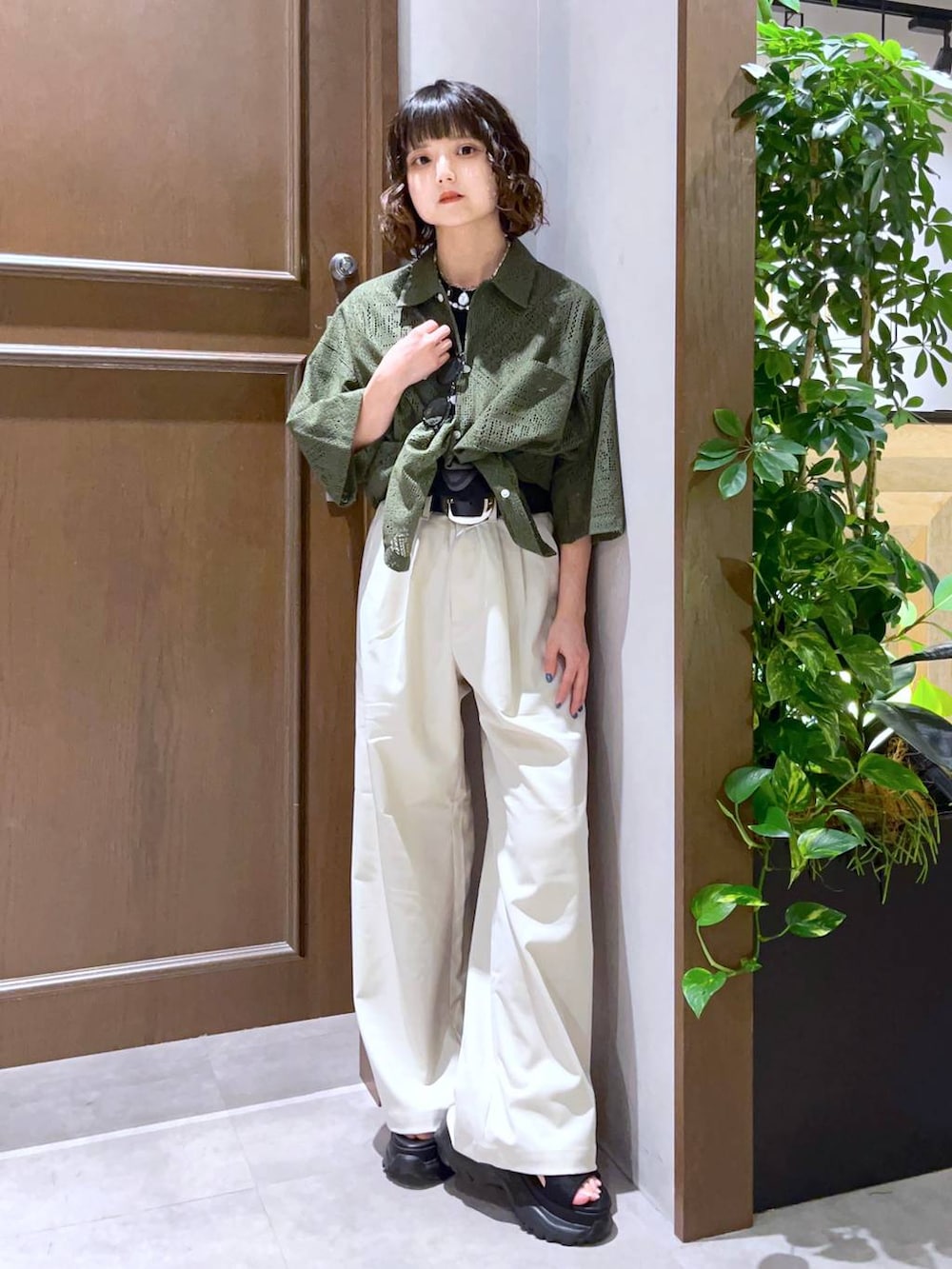 ホワイト系のスラックス、グリーン系のシャツ/ブラウス、ブラック系のサンダルを着用したレディースの夏コーディネートの2枚目の写真