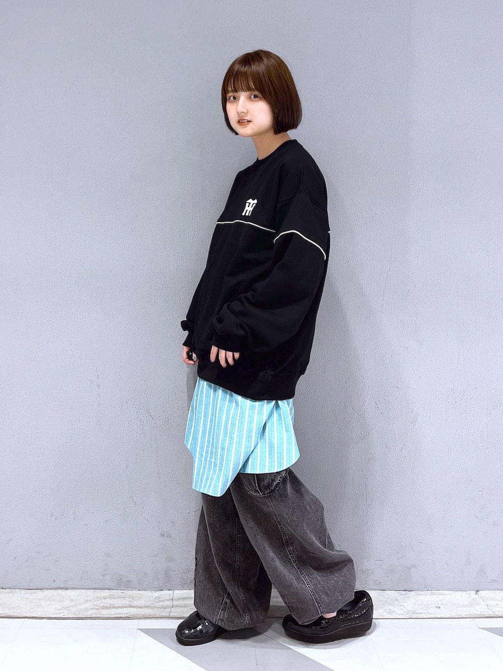 グレー系のデニムパンツ、ブラック系のスウェット、グリーン系のシャツ/ブラウスを着用したレディースの春コーディネートの3枚目の写真