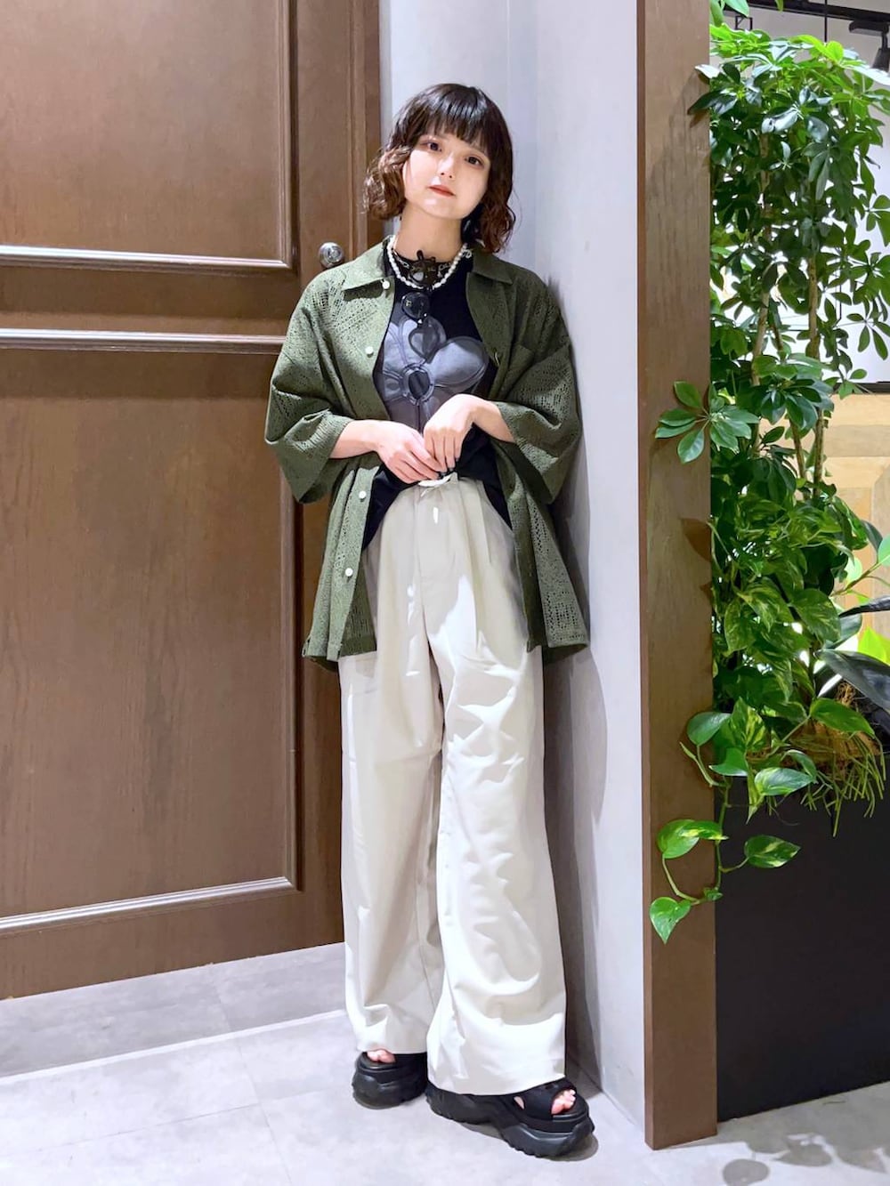 ホワイト系のスラックス、グリーン系のシャツ/ブラウス、ブラック系のTシャツ/カットソーを着用したレディースの夏コーディネートの3枚目の写真