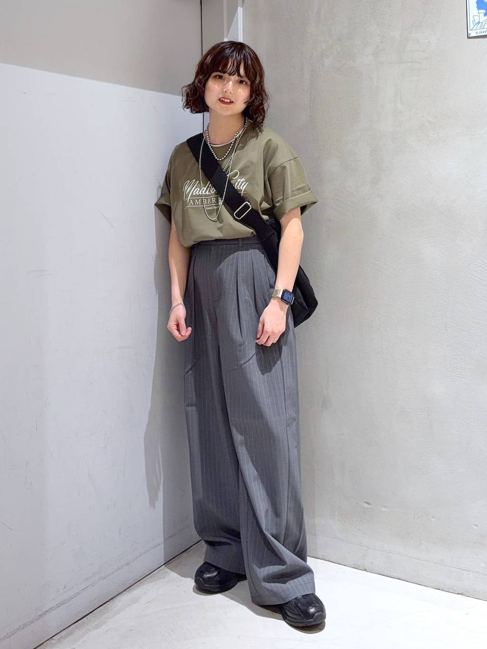ブラック系のショルダーバッグ、グリーン系のTシャツ/カットソー、ブラック系のスニーカーを着用したレディースの夏コーディネートの2枚目の写真