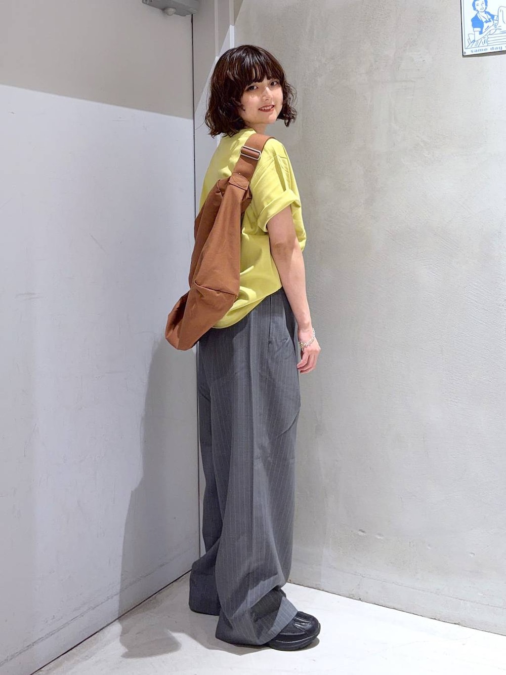 ブラック系のショルダーバッグ、グレー系のその他パンツ、イエロー系のTシャツ/カットソーを着用したレディースの夏コーディネートの4枚目の写真