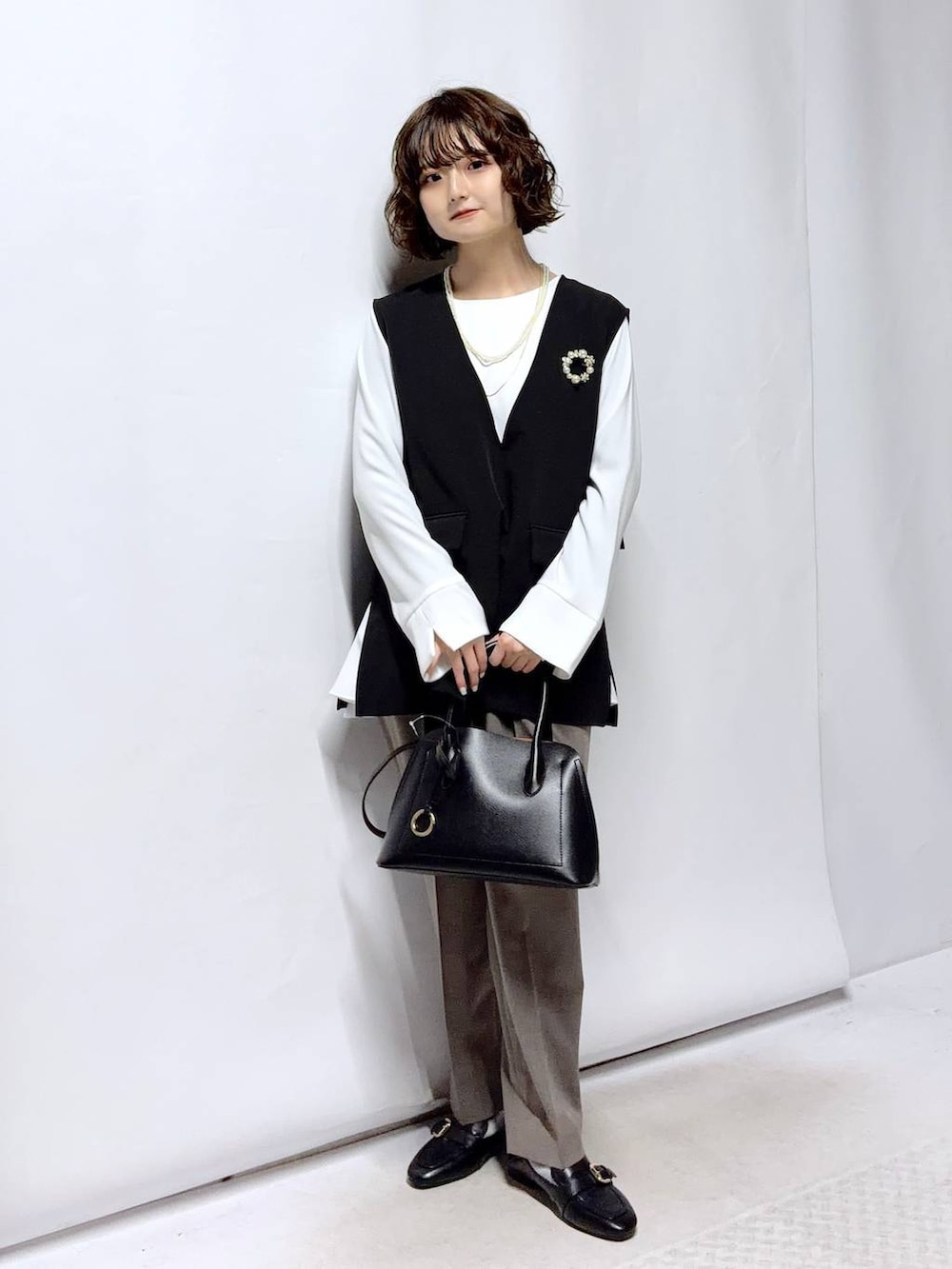 ブラック系のローファー、ブラック系のショルダーバッグ、ブラウン系のスラックスを着用したレディースの冬コーディネートの3枚目の写真