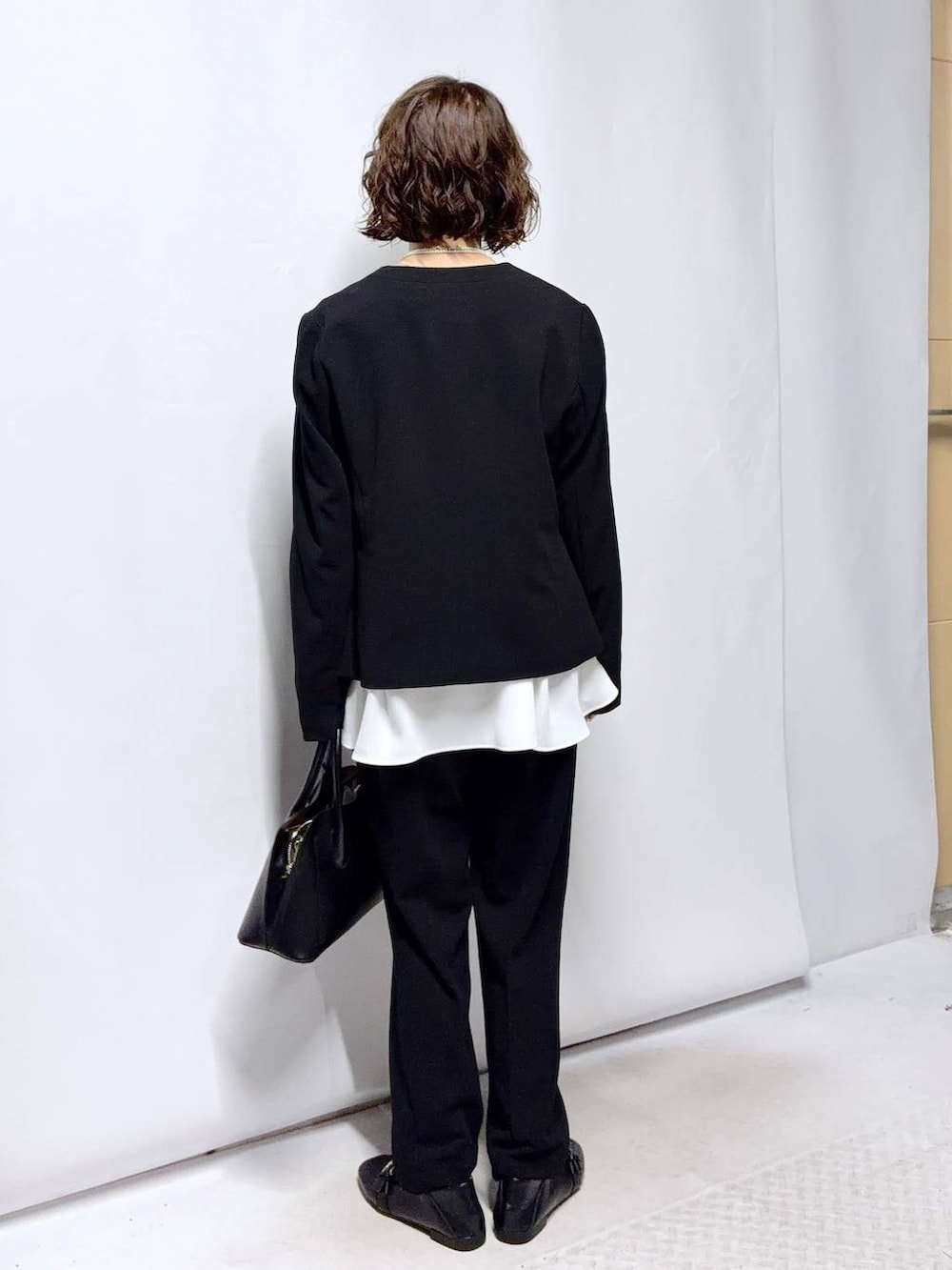 ブラック系のローファー、ブラック系のショルダーバッグ、ブラック系のセットアップを着用したレディースの冬コーディネートの4枚目の写真