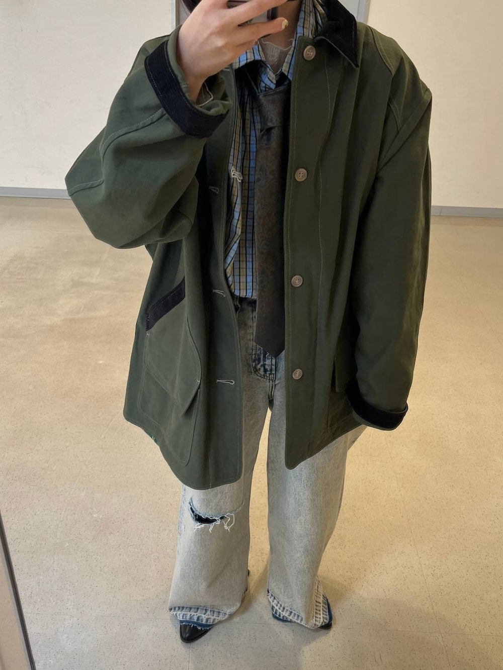 ブラウン系のネクタイ、ブラック系のブーツ、グリーン系のミリタリージャケットを着用したレディースの冬コーディネートの2枚目の写真