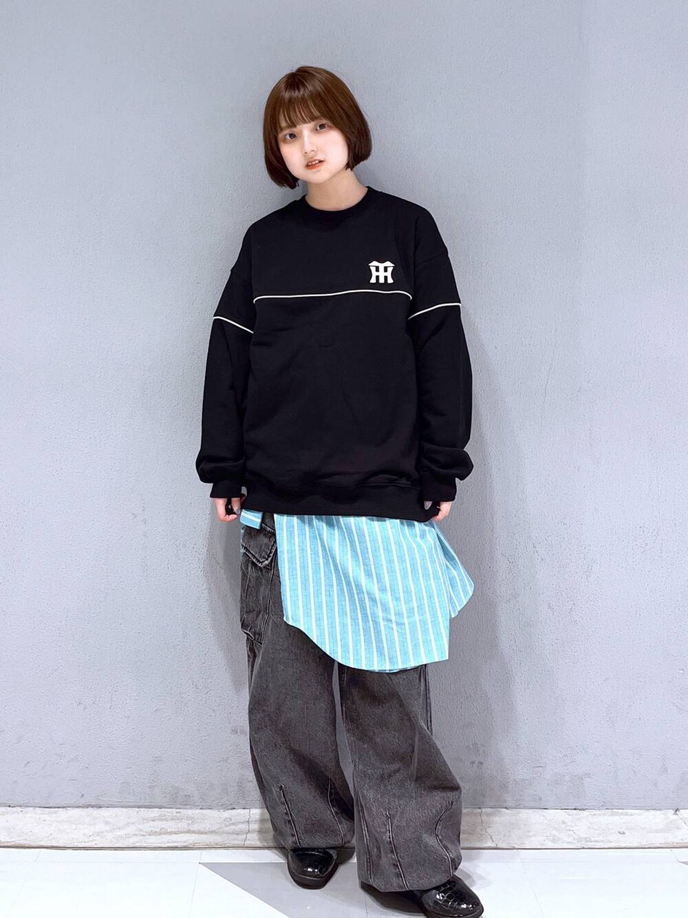 グレー系のデニムパンツ、ブラック系のスウェット、グリーン系のシャツ/ブラウスを着用したレディースの春コーディネートの2枚目の写真