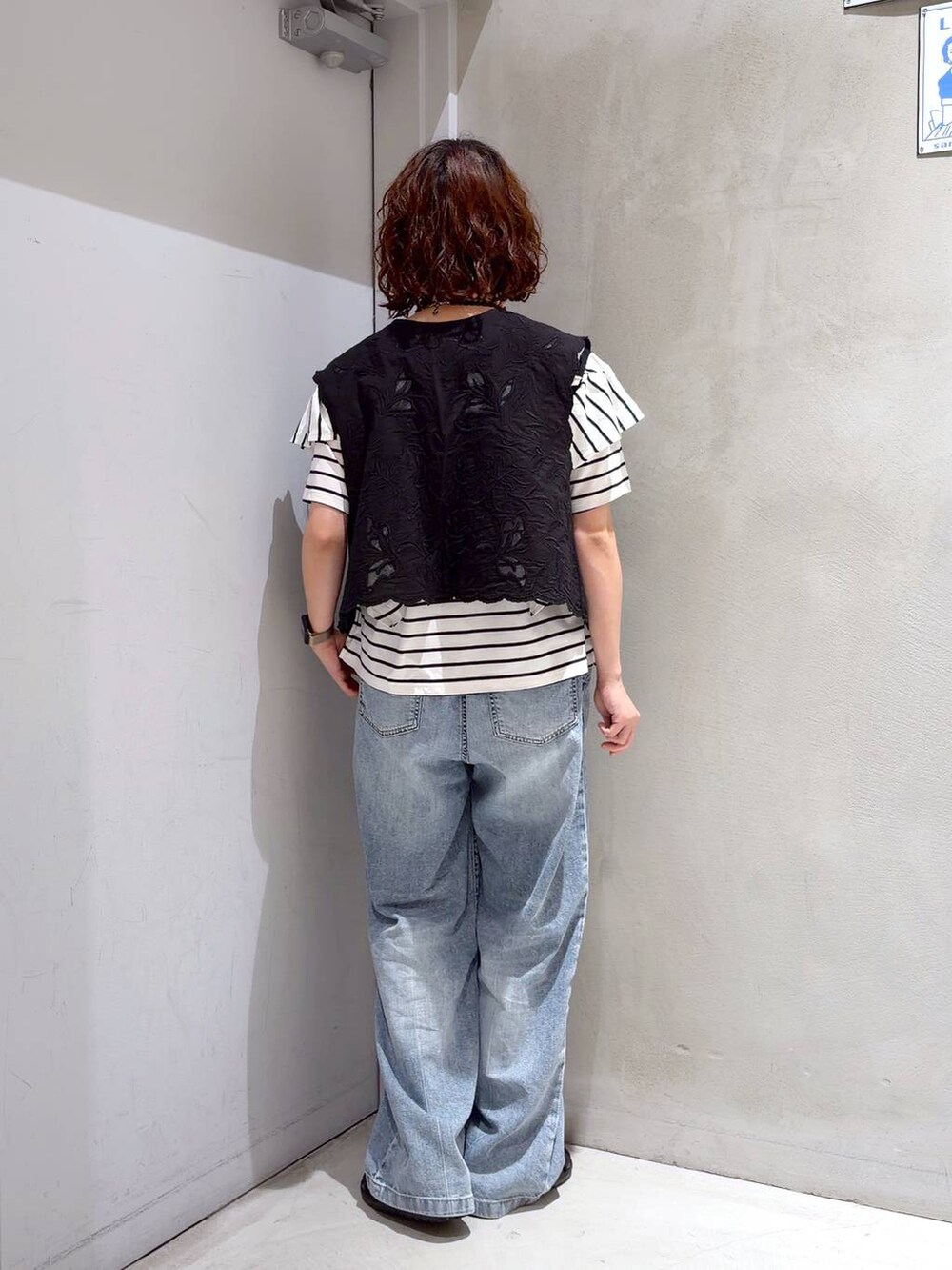 ブラック系のベスト、ブルー系のデニムパンツ、ブラック系のサンダルを着用したレディースの夏コーディネートの4枚目の写真