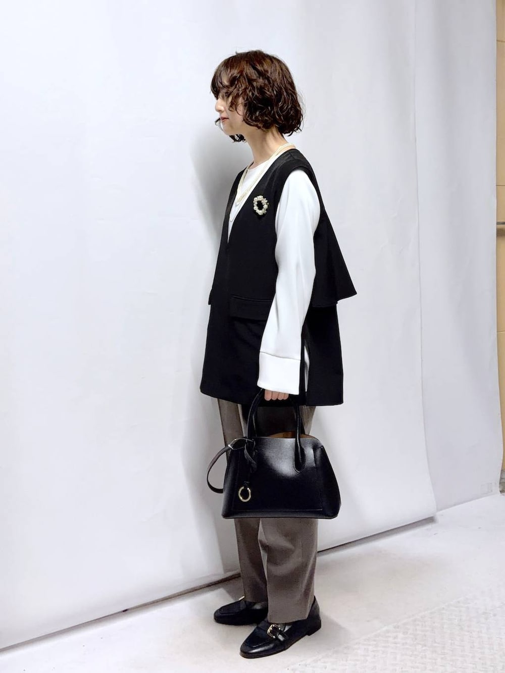 ブラック系のローファー、ブラック系のショルダーバッグ、ブラウン系のスラックスを着用したレディースの冬コーディネートの4枚目の写真