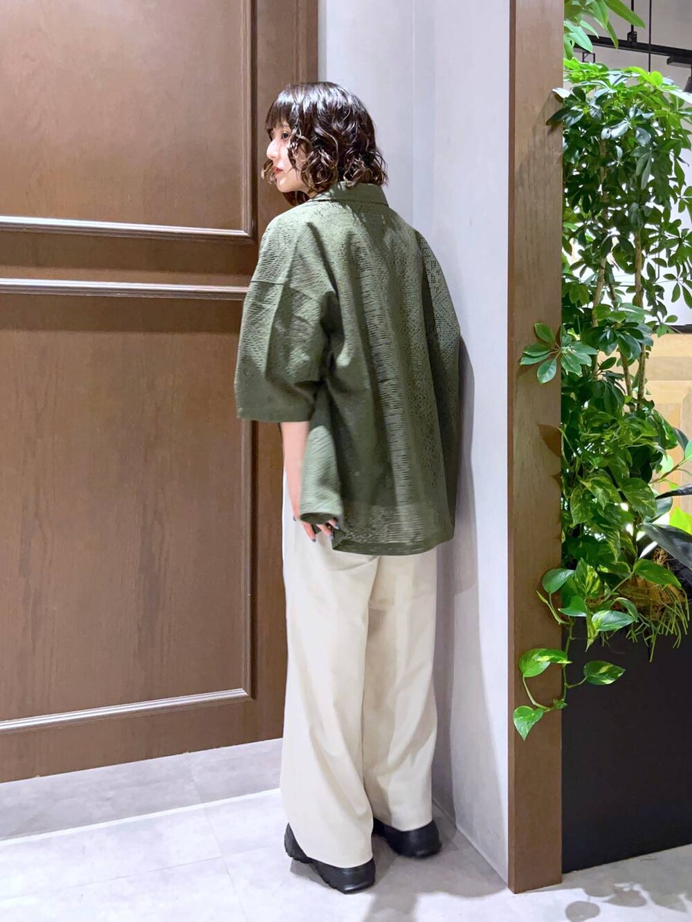 ホワイト系のスラックス、グリーン系のシャツ/ブラウス、ブラック系のサンダルを着用したレディースの夏コーディネートの3枚目の写真