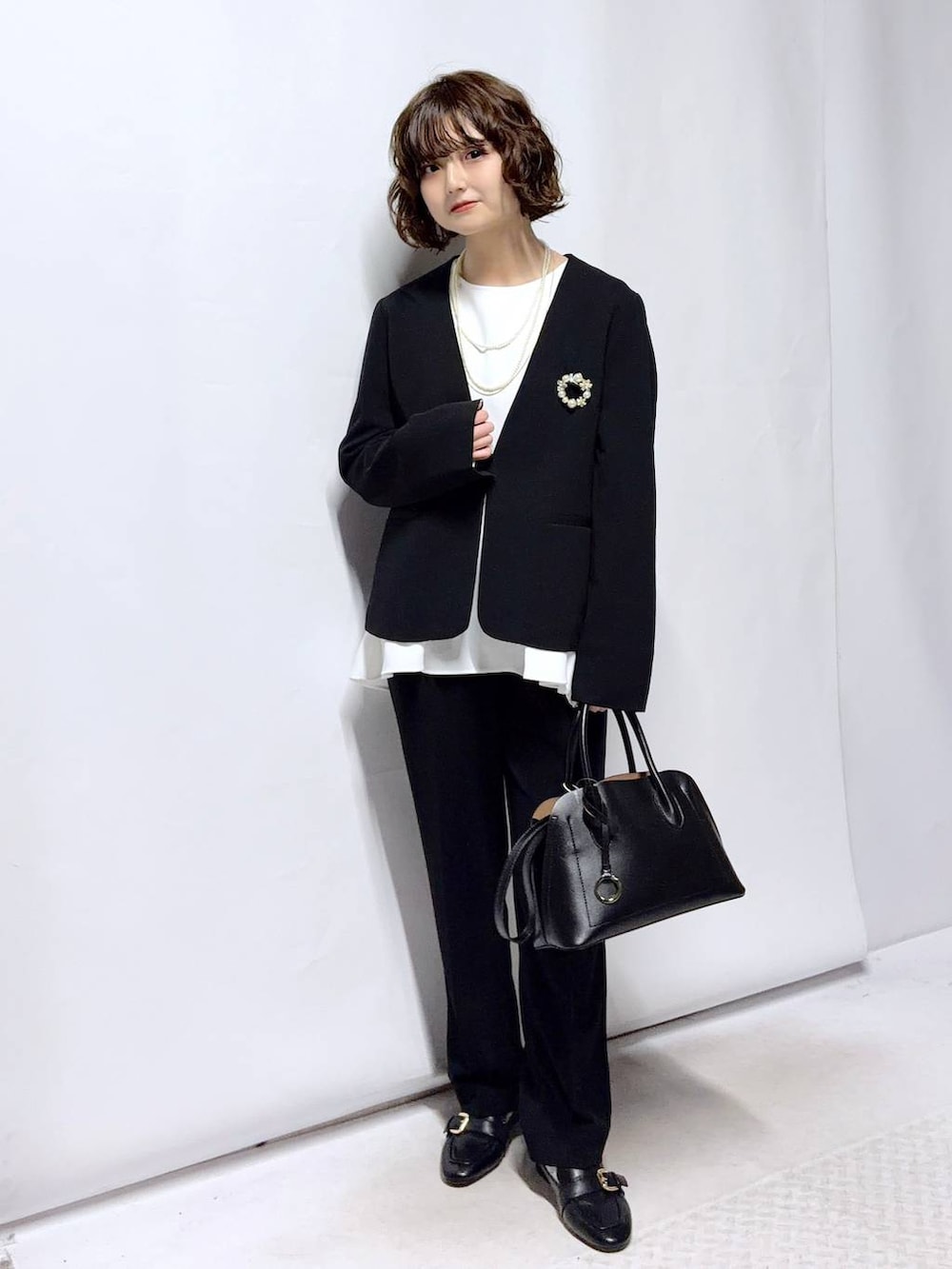 ブラック系のローファー、ブラック系のショルダーバッグ、ブラック系のセットアップを着用したレディースの冬コーディネートの2枚目の写真