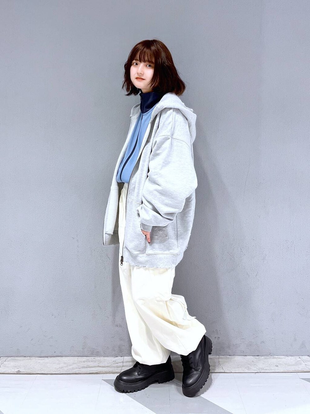 グレー系のパーカー、ブラック系のブーツ、ブルー系のブルゾンを着用したレディースの冬コーディネートの3枚目の写真