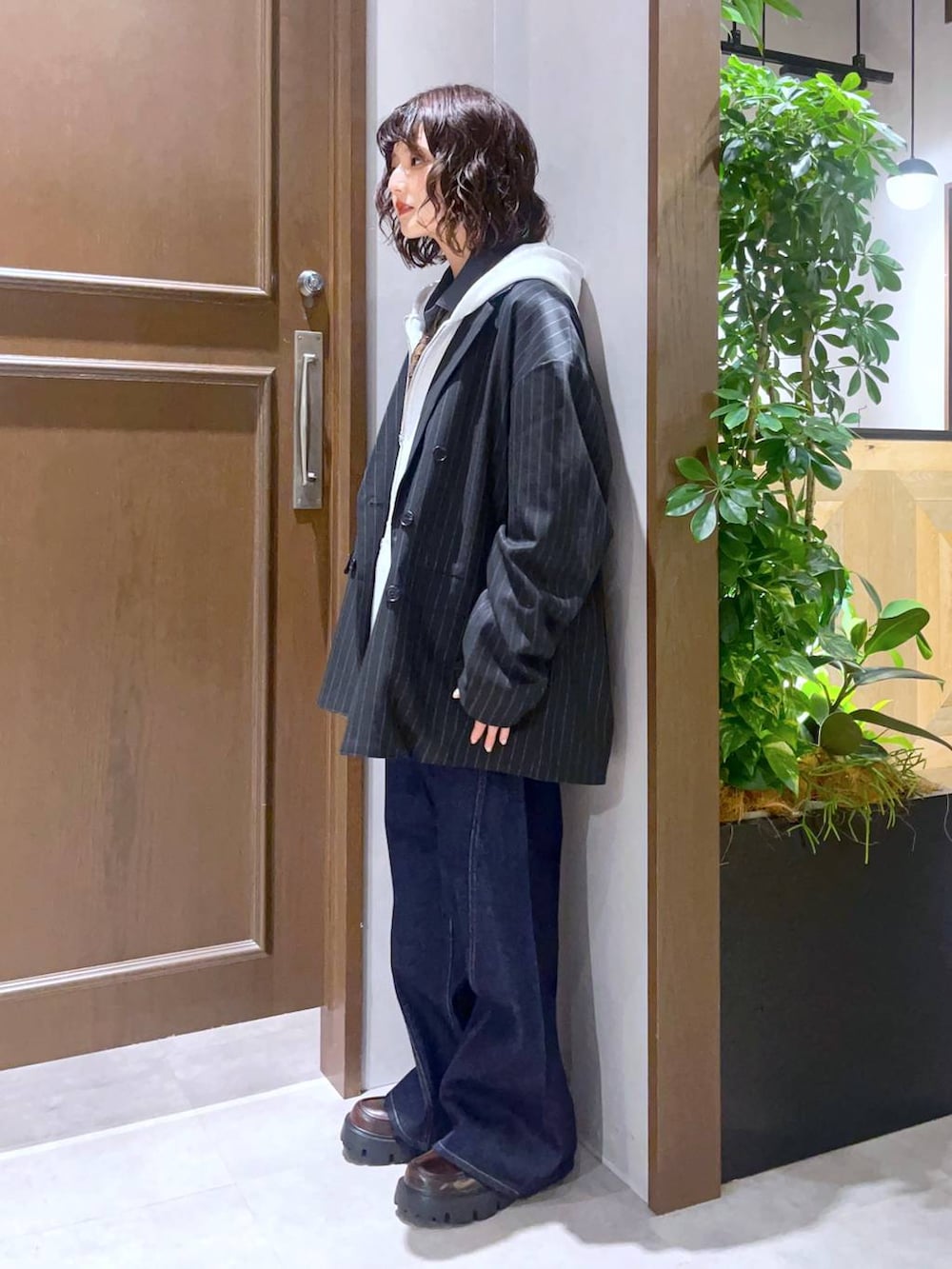 グレー系のシャツ/ブラウス、ブラウン系のローファー、ブルー系のデニムパンツを着用したレディースの秋コーディネートの2枚目の写真