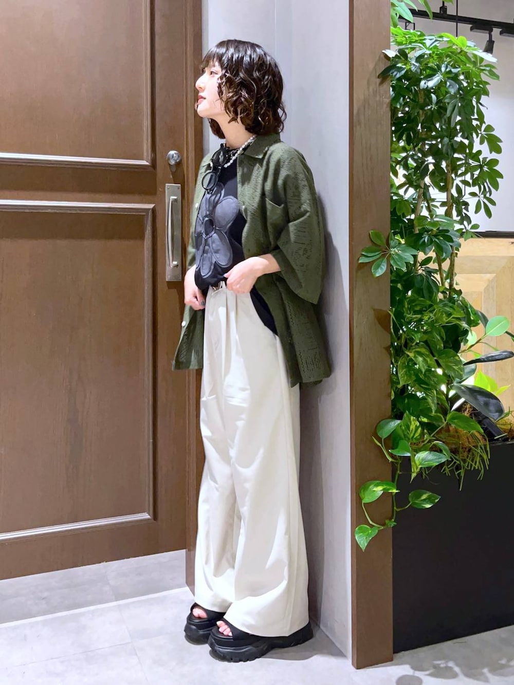 ホワイト系のスラックス、グリーン系のシャツ/ブラウス、ブラック系のTシャツ/カットソーを着用したレディースの夏コーディネートの4枚目の写真