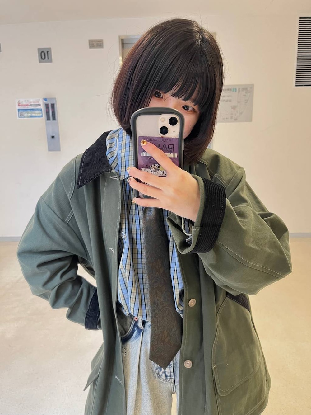 ブラウン系のネクタイ、ブラック系のブーツ、グリーン系のミリタリージャケットを着用したレディースの冬コーディネートの3枚目の写真