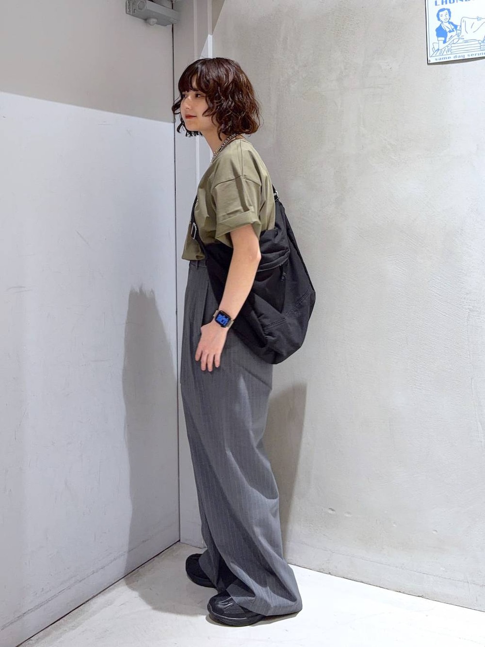ブラック系のショルダーバッグ、グリーン系のTシャツ/カットソー、ブラック系のスニーカーを着用したレディースの夏コーディネートの4枚目の写真
