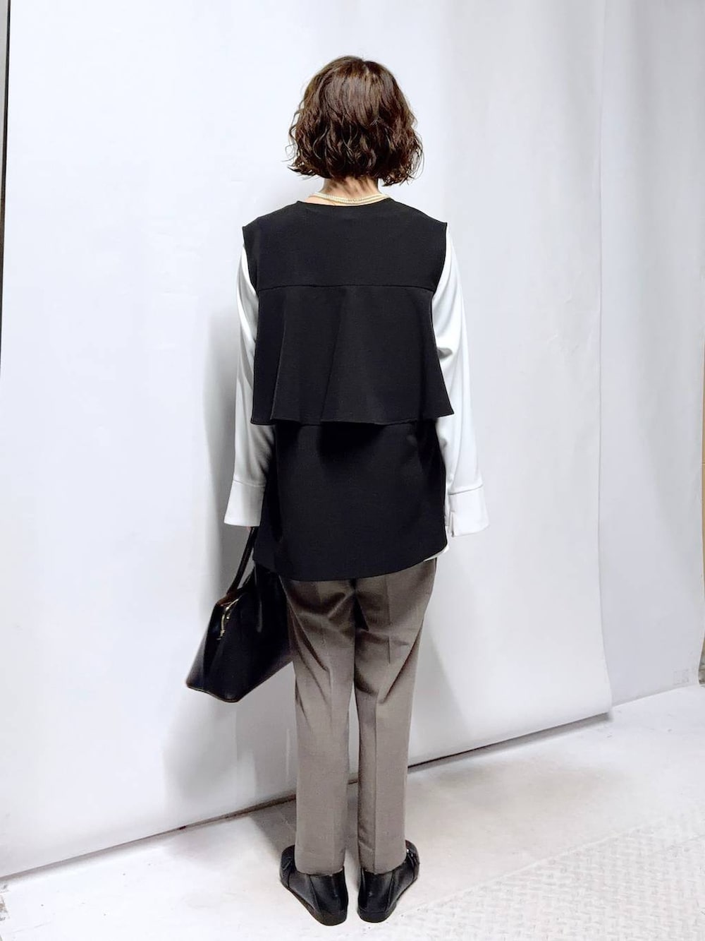 ブラック系のローファー、ブラック系のショルダーバッグ、ブラウン系のスラックスを着用したレディースの冬コーディネートの5枚目の写真