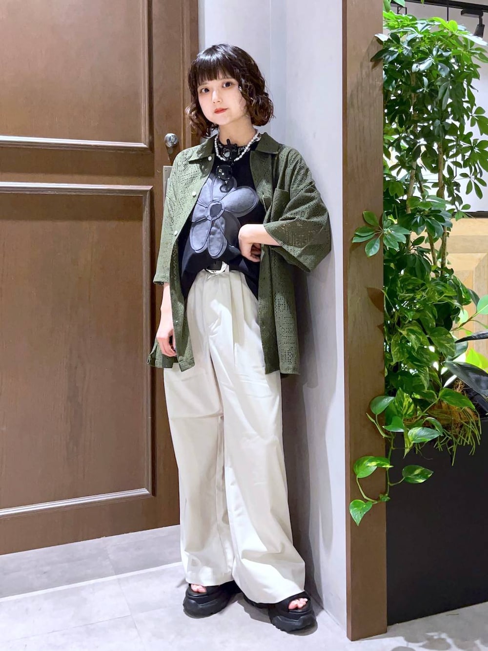 ホワイト系のスラックス、グリーン系のシャツ/ブラウス、ブラック系のTシャツ/カットソーを着用したレディースの夏コーディネートの2枚目の写真