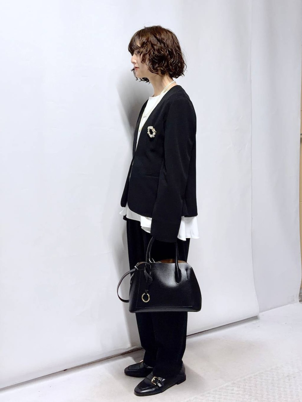 ブラック系のローファー、ブラック系のショルダーバッグ、ブラック系のセットアップを着用したレディースの冬コーディネートの3枚目の写真