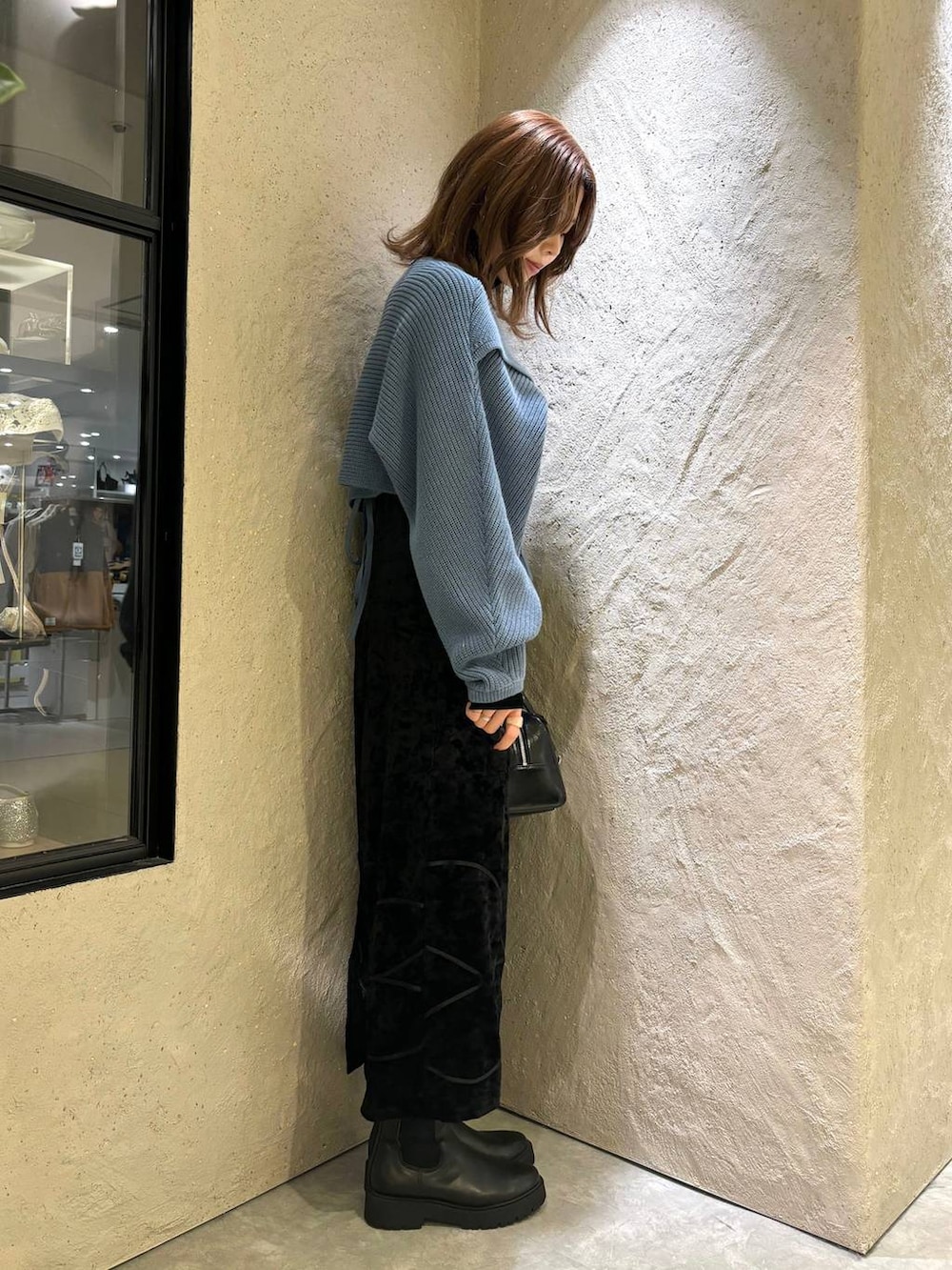 ブルー系のニット/セーター、ブラック系のブーツ、ブラック系のボストンバッグを着用したレディースの秋コーディネートの4枚目の写真
