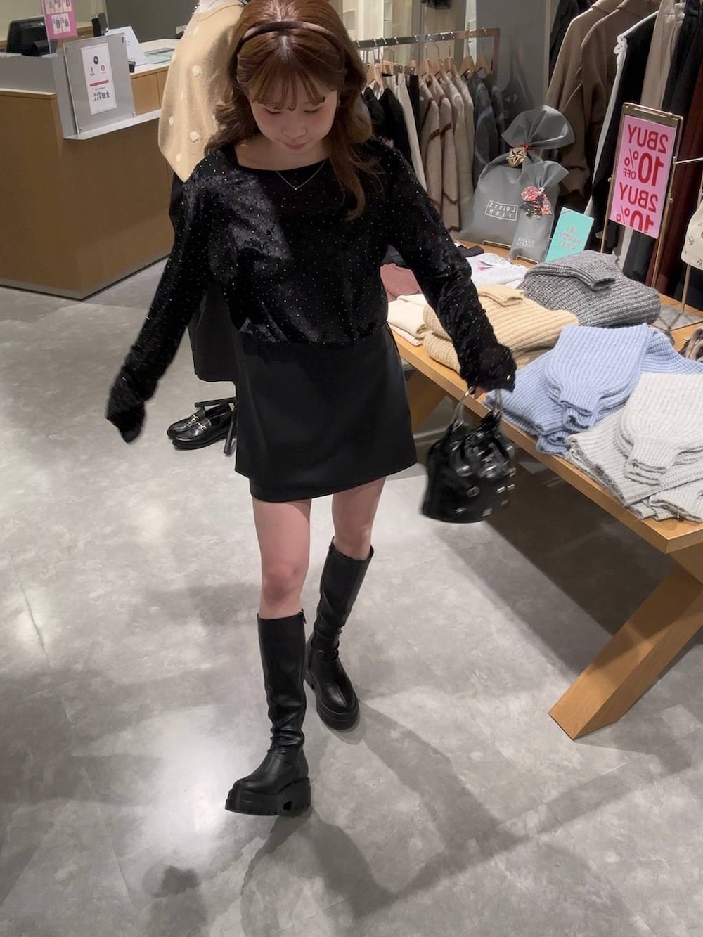 ブラック系のスカート、ブラック系のブーツ、ブラック系のハンドバッグを着用したレディースの冬コーディネートの5枚目の写真