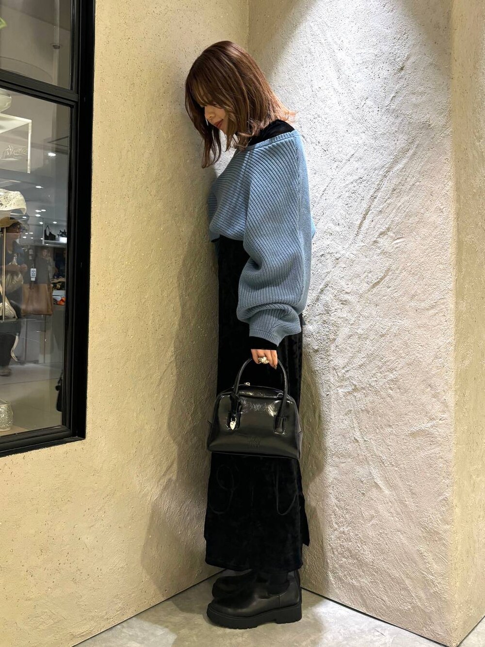ブルー系のニット/セーター、ブラック系のブーツ、ブラック系のボストンバッグを着用したレディースの秋コーディネートの3枚目の写真