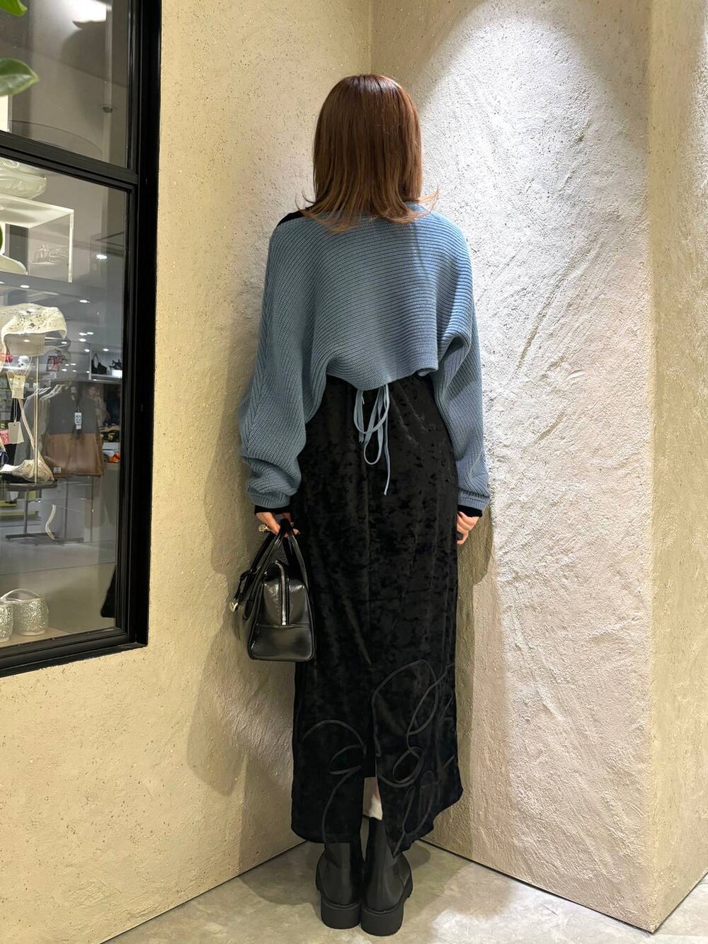 ブルー系のニット/セーター、ブラック系のブーツ、ブラック系のボストンバッグを着用したレディースの秋コーディネートの2枚目の写真
