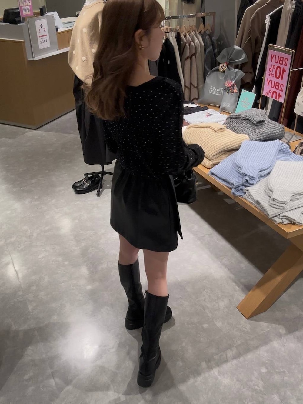 ブラック系のスカート、ブラック系のブーツ、ブラック系のハンドバッグを着用したレディースの冬コーディネートの4枚目の写真