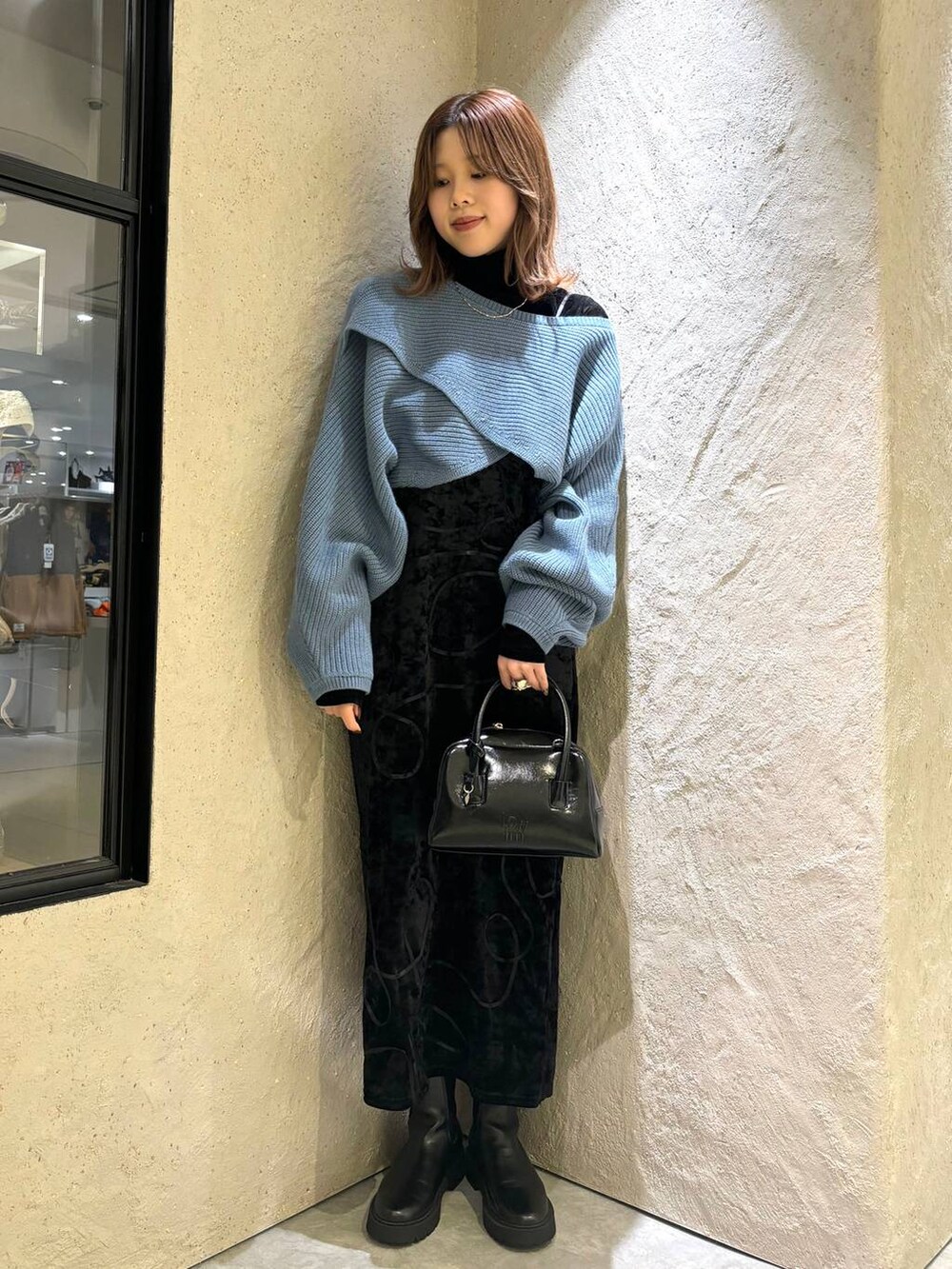 ブルー系のニット/セーター、ブラック系のブーツ、ブラック系のボストンバッグを着用したレディースの秋コーディネートの5枚目の写真