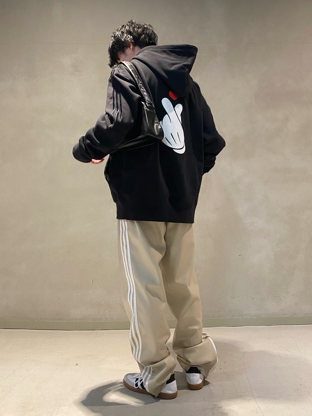 ブラック系のパーカー、ブラック系のショルダーバッグ、ベージュ系のスウェットパンツを着用したメンズの冬コーディネートの2枚目の写真