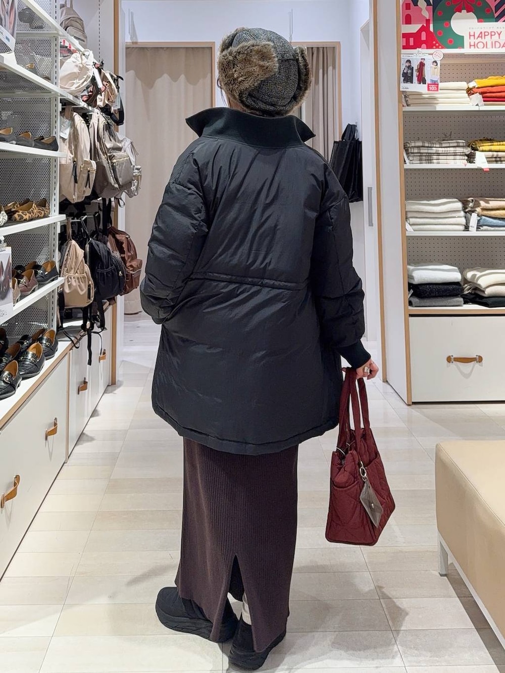 レッド系のトートバッグ、ブラック系のダウンジャケット/コート、レッド系のニット/セーターを着用したレディースの冬コーディネートの7枚目の写真