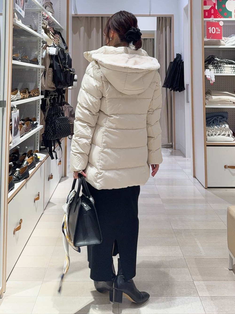 ベージュ系のダウンジャケット/コート、ブラック系のショルダーバッグ、ブラウン系のニット/セーターを着用したレディースの冬コーディネートの5枚目の写真