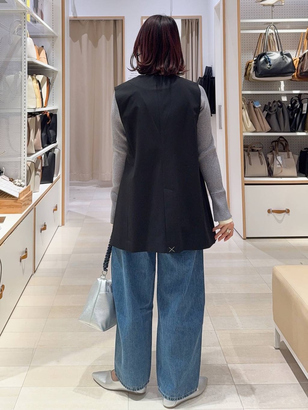 シルバー系のパンプス、ブラック系のその他アウター、ブルー系のデニムパンツを着用したレディースの冬コーディネートの7枚目の写真