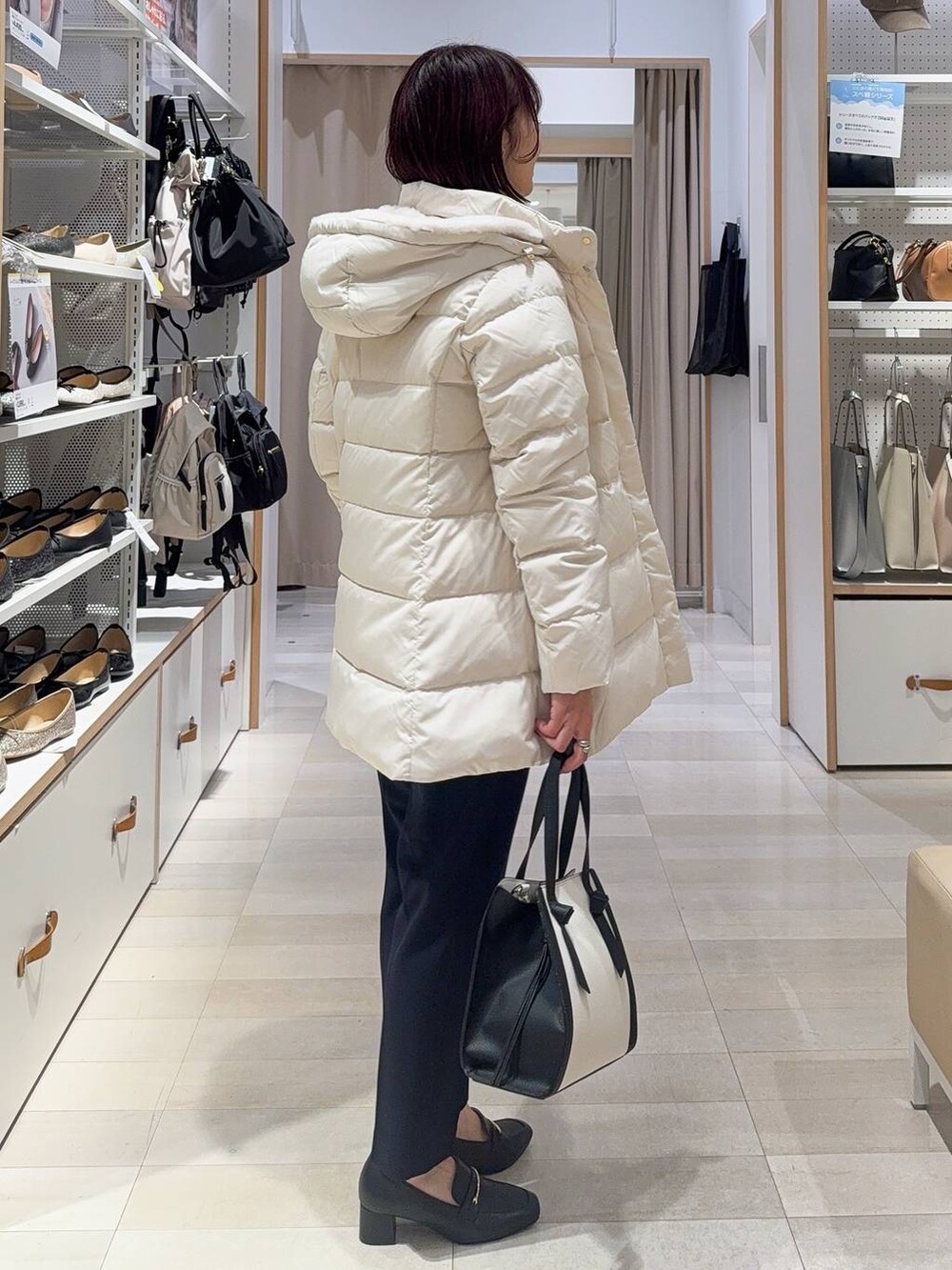 ブラック系のローファー、ホワイト系のショルダーバッグ、ベージュ系のダウンジャケット/コートを着用したレディースの秋コーディネートの4枚目の写真