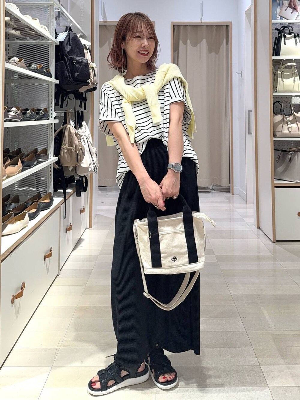 ブラック系のショルダーバッグ、ブラック系のスカート、ブラック系のサンダルを着用したレディースの夏コーディネートの2枚目の写真