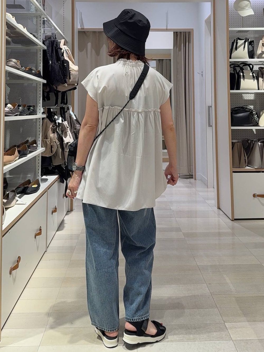 ブルー系のデニムパンツ、ブラック系のショルダーバッグ、ブラック系のサンダルを着用したレディースの夏コーディネートの4枚目の写真