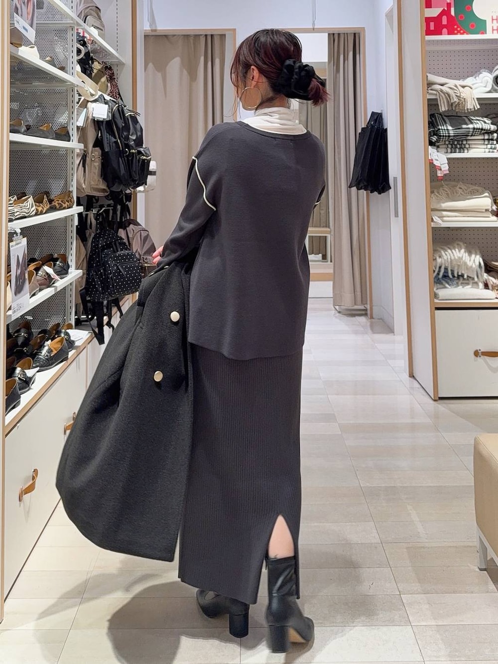 ブラウン系のボストンバッグ、ブラック系のチェスターコート、ホワイト系のTシャツ/カットソーを着用したレディースの冬コーディネートの9枚目の写真