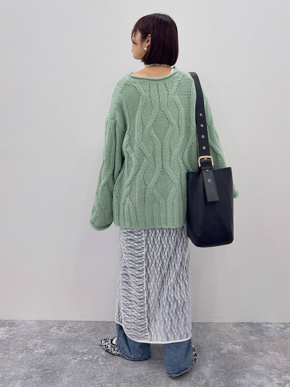 ブラック系のショルダーバッグ、ホワイト系のワンピース、ブルー系のデニムパンツを着用したレディースの秋コーディネートの3枚目の写真