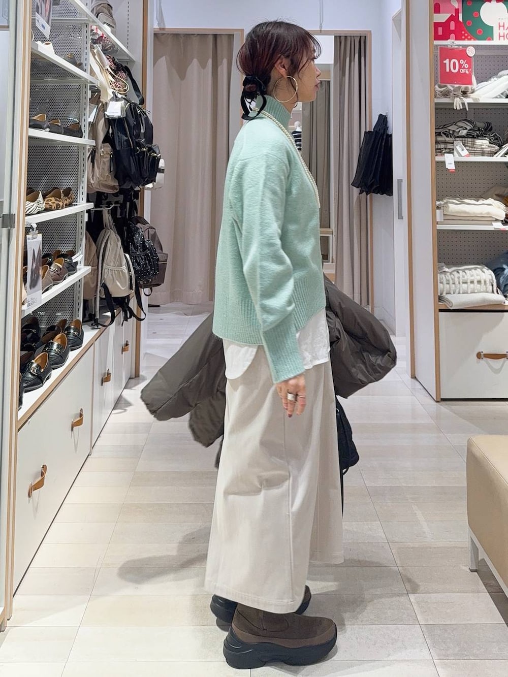 ブラウン系のダウンジャケット/コート、グレー系のスカート、ブラック系のハンドバッグを着用したレディースの冬コーディネートの8枚目の写真