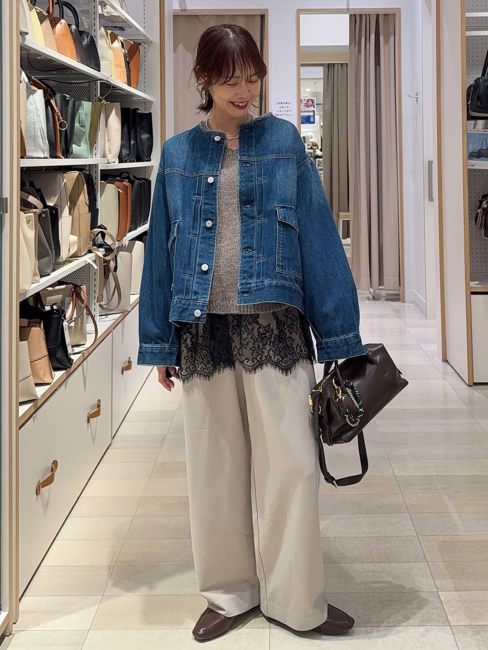 ブルー系のデニムジャケット、ブラウン系のボストンバッグ、ベージュ系のその他パンツを着用したレディースの春コーディネートの2枚目の写真