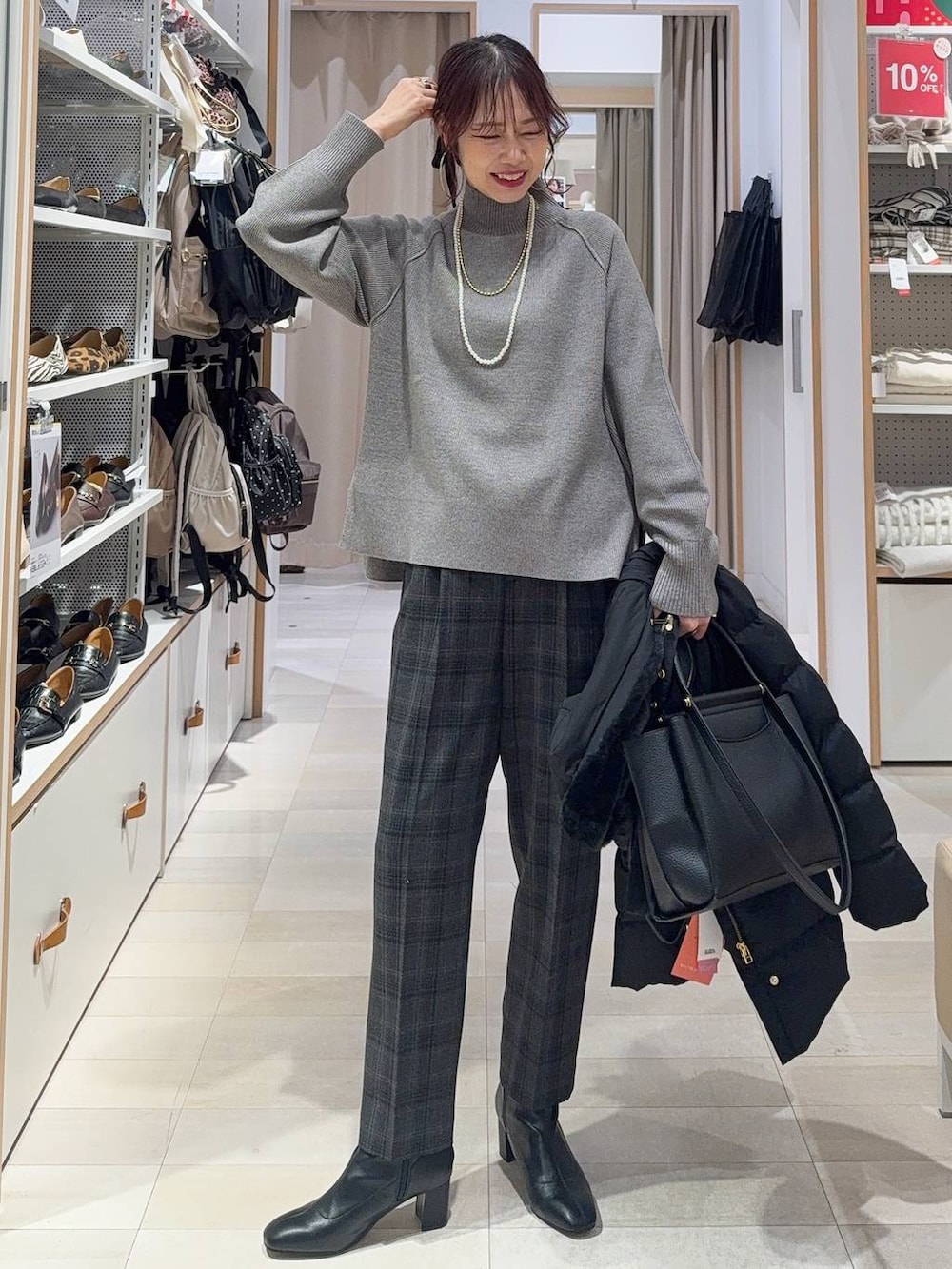 グリーン系のショルダーバッグ、ブラック系のステンカラーコート、ホワイト系のTシャツ/カットソーを着用したレディースの冬コーディネートの3枚目の写真