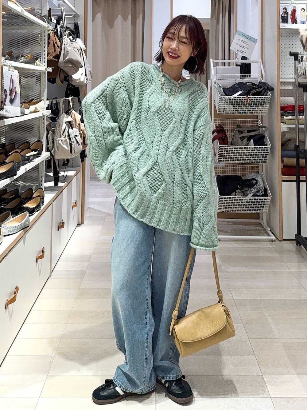 ブルー系のデニムパンツ、イエロー系のショルダーバッグ、ホワイト系のステンカラーコートを着用したレディースの冬コーディネートの2枚目の写真