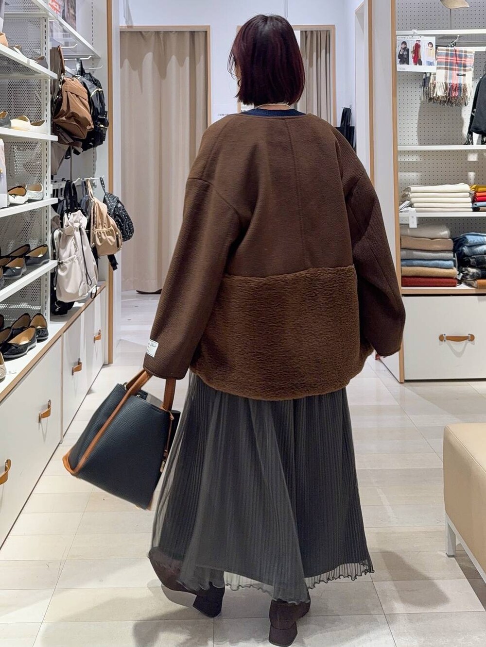 ブラック系のトートバッグ、ブラウン系のノーカラージャケット、シルバー系のネックレスを着用したレディースの秋コーディネートの4枚目の写真