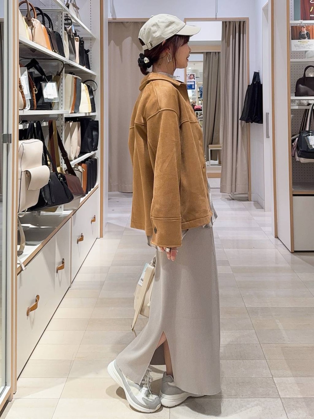 ホワイト系のショルダーバッグ、ホワイト系のスニーカー、ブラウン系のテーラードジャケットを着用したレディースの冬コーディネートの4枚目の写真